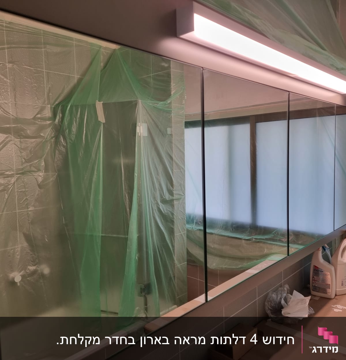 מראה גדולה עם תאורה עליונה בחדר אמבטיה